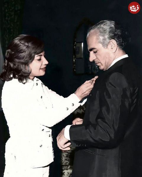 عکسی زیر خاکی از اشرف پهلوی در حال نصب مدال بر سینه برادر دو قلویش